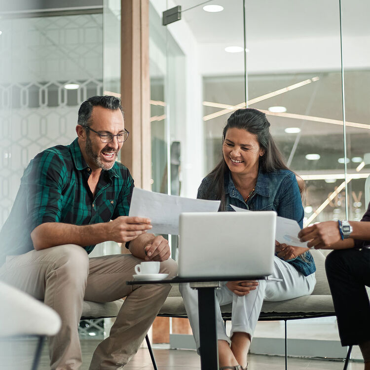Couple meeting with a mortgage advisor, reviewing documents and smiling.