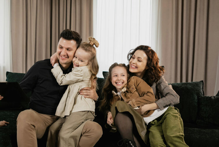 Family sitting together on the couch, smiling and enjoying their time at home.