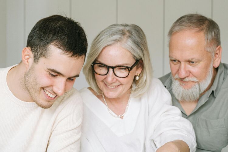 Young man smiling with his parents while reviewing documents at home.