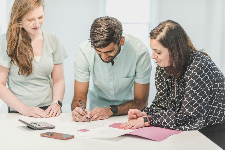 Couple signing mortgage documents with the guidance of a Nest Home Loans advisor